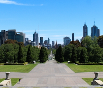 A clear day in Melbourne, showing an empty park with towering skyscrapers in the distance